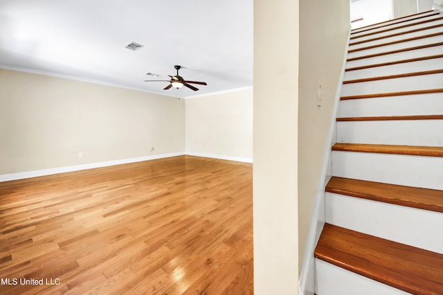 stairway featuring crown molding, wood-type flooring, and ceiling fan