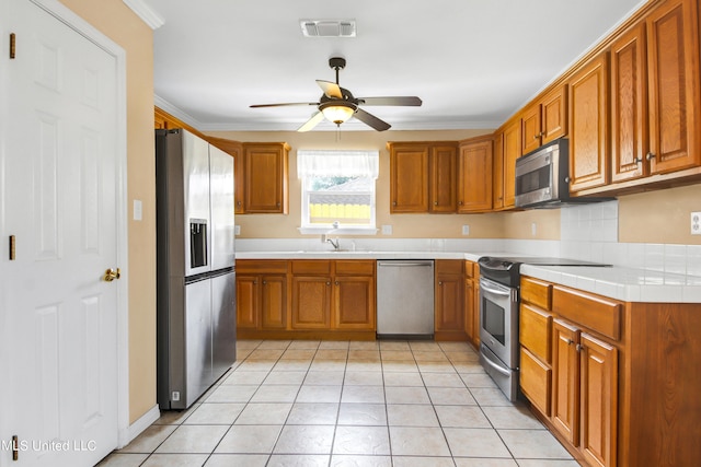 kitchen featuring sink, light tile patterned flooring, ceiling fan, stainless steel appliances, and crown molding