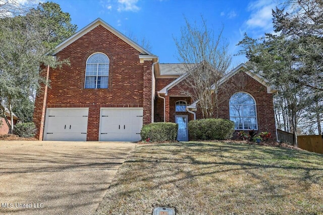 traditional home with an attached garage, concrete driveway, brick siding, and a front yard