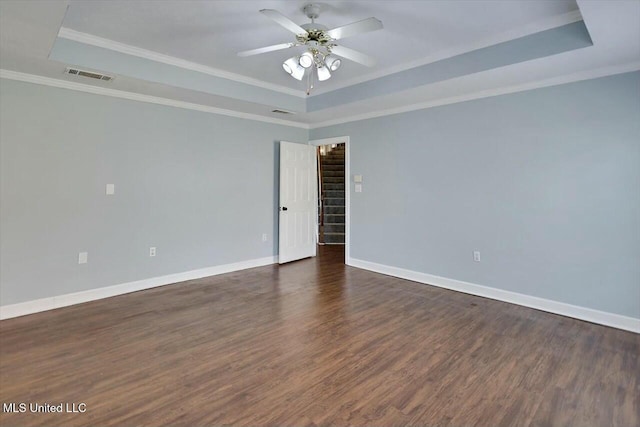 empty room featuring dark wood-style floors, a raised ceiling, and visible vents