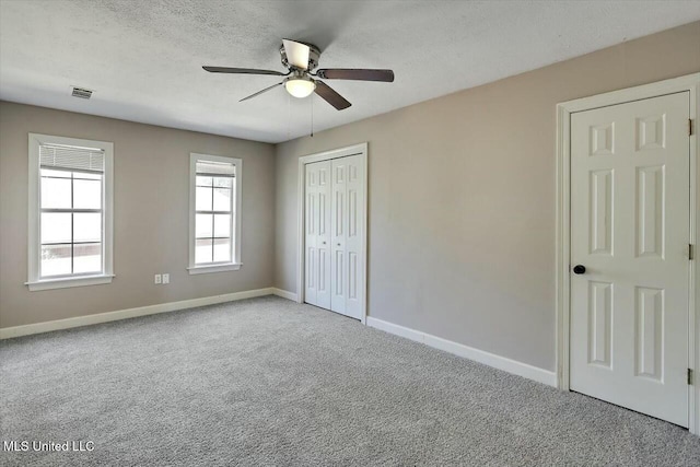 unfurnished bedroom featuring a closet, visible vents, carpet flooring, a textured ceiling, and baseboards