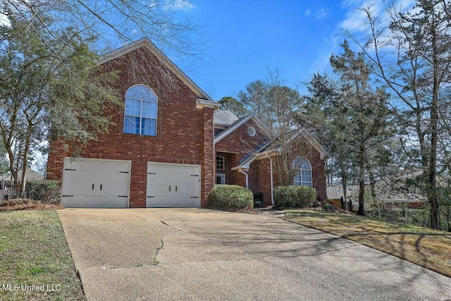 traditional-style house featuring an attached garage, concrete driveway, and brick siding