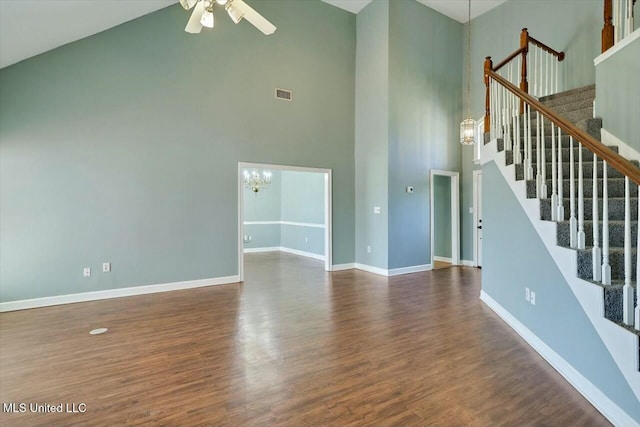 unfurnished living room featuring baseboards, visible vents, a towering ceiling, stairway, and wood finished floors