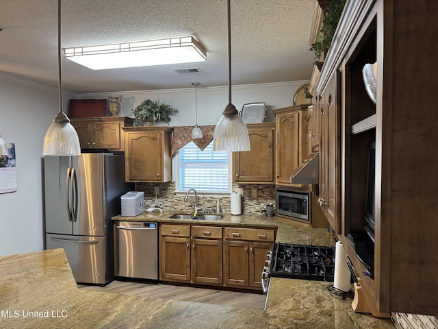 kitchen with visible vents, brown cabinetry, appliances with stainless steel finishes, under cabinet range hood, and a sink