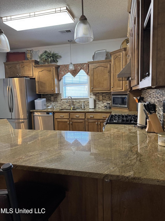 kitchen featuring crown molding, stainless steel appliances, decorative backsplash, stone countertops, and a sink