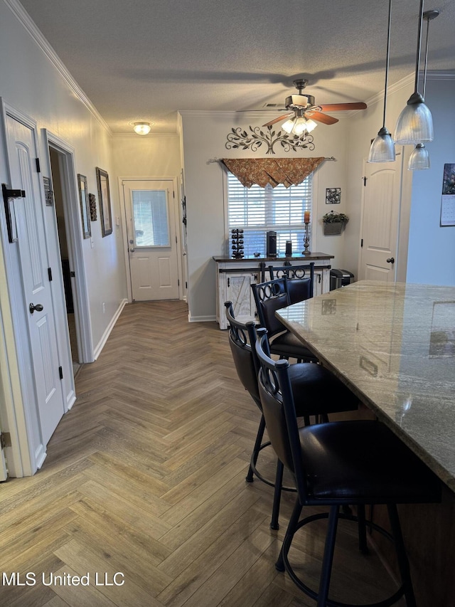 dining space with ceiling fan, a textured ceiling, baseboards, and crown molding