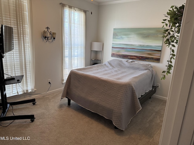 carpeted bedroom with crown molding and baseboards