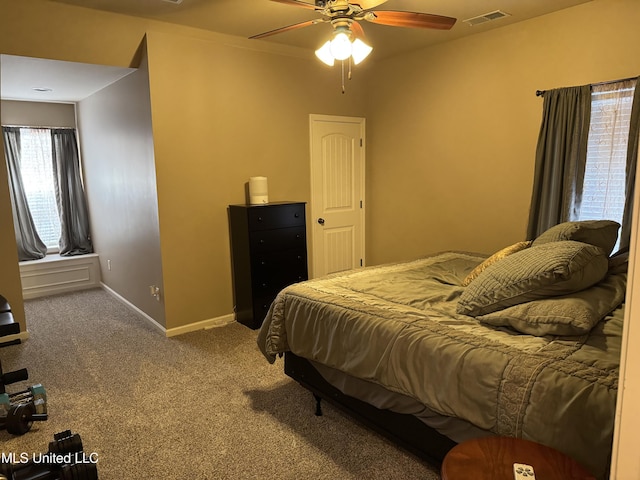 carpeted bedroom featuring a ceiling fan, visible vents, and baseboards