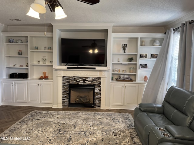 living room with a textured ceiling, ceiling fan, ornamental molding, and a fireplace