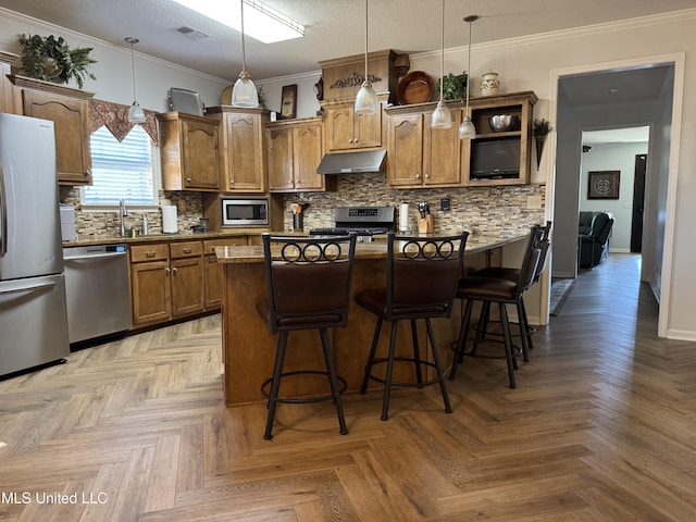 kitchen featuring a kitchen breakfast bar, appliances with stainless steel finishes, visible vents, and under cabinet range hood