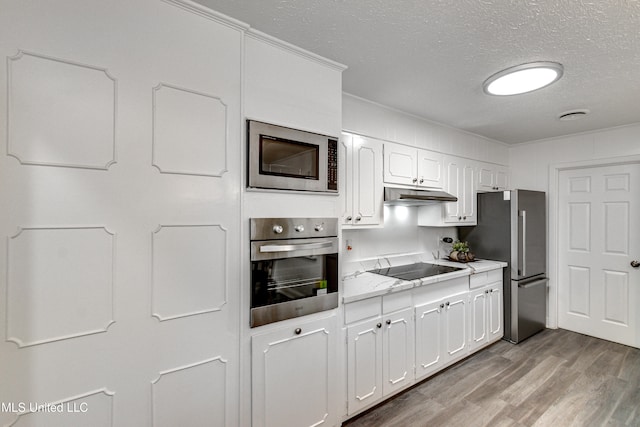 kitchen with appliances with stainless steel finishes, a textured ceiling, light hardwood / wood-style flooring, and white cabinetry