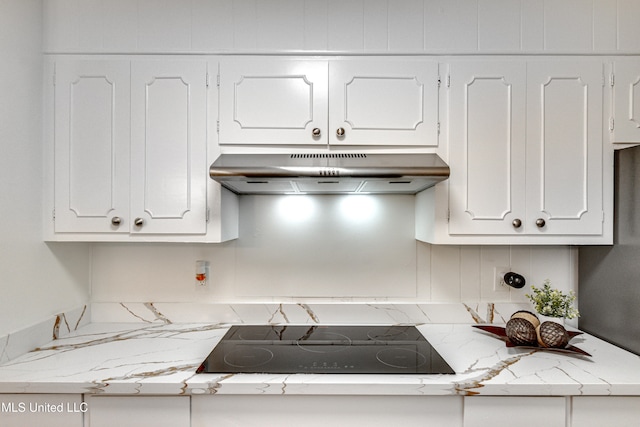 kitchen with black electric cooktop, light stone counters, and white cabinets