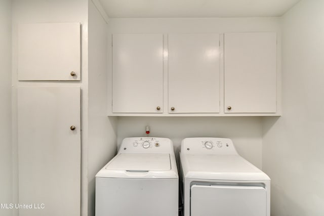 clothes washing area with separate washer and dryer and cabinets