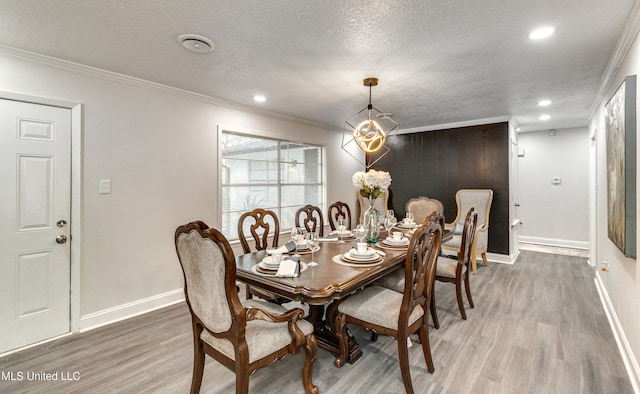 dining area featuring crown molding, wood-type flooring, a textured ceiling, and an inviting chandelier