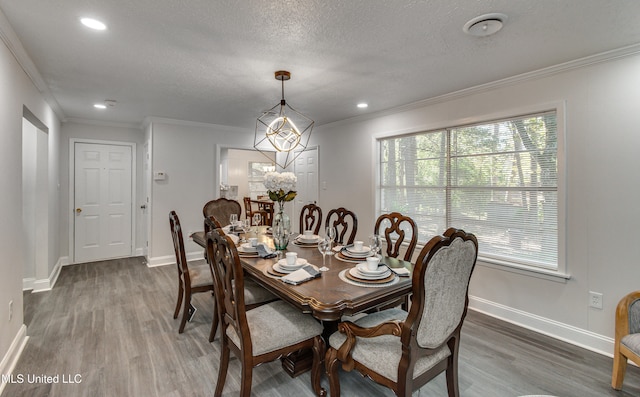 dining area with wood-type flooring, a textured ceiling, and crown molding