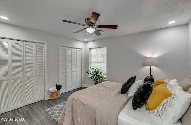 bedroom featuring a textured ceiling, ceiling fan, two closets, and hardwood / wood-style flooring