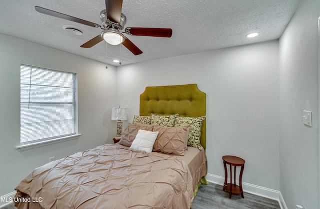 bedroom with ceiling fan, dark hardwood / wood-style flooring, and a textured ceiling