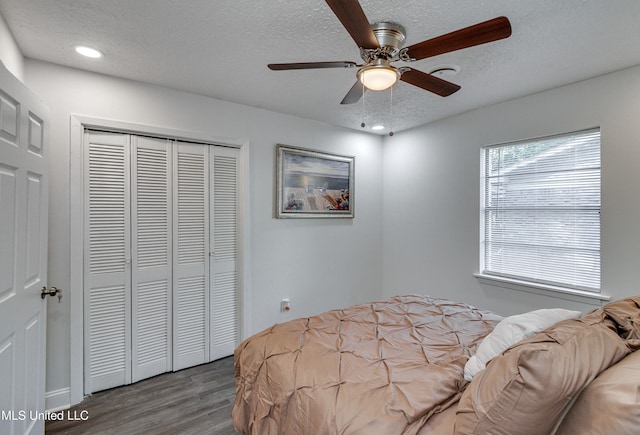 bedroom featuring hardwood / wood-style floors, a textured ceiling, a closet, and ceiling fan