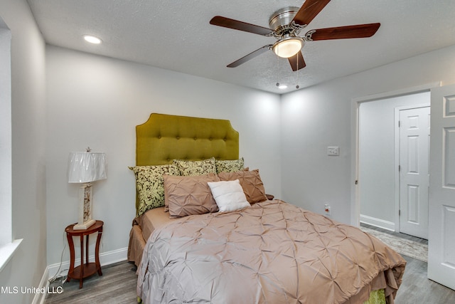 bedroom featuring ceiling fan, hardwood / wood-style floors, and a textured ceiling