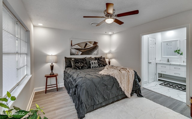 bedroom featuring ceiling fan, light hardwood / wood-style floors, a textured ceiling, and connected bathroom