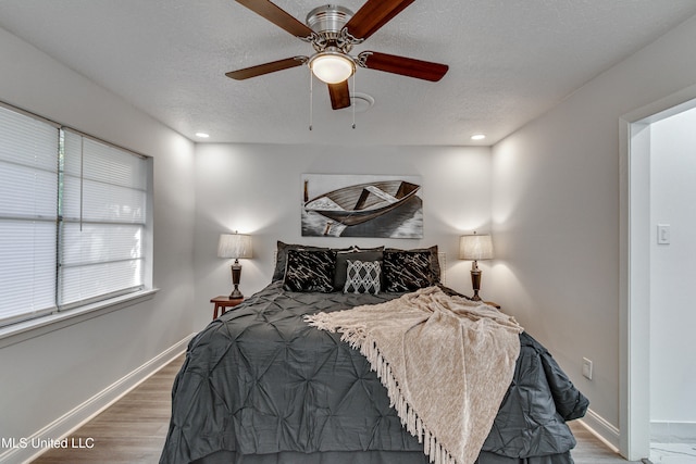 bedroom with ceiling fan, dark hardwood / wood-style flooring, and a textured ceiling