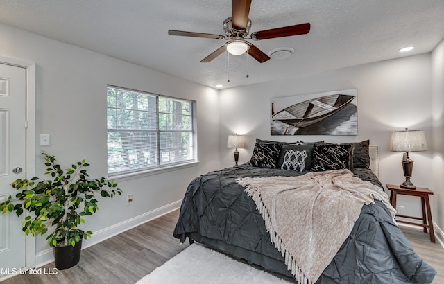 bedroom featuring ceiling fan, wood-type flooring, and a textured ceiling