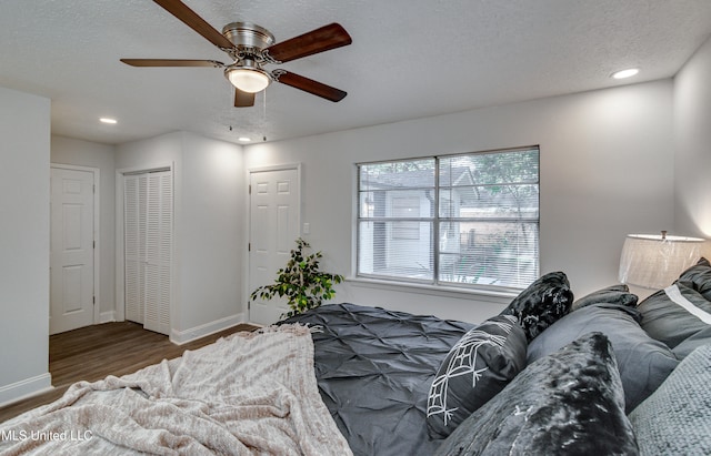 bedroom with a textured ceiling, dark hardwood / wood-style flooring, and ceiling fan