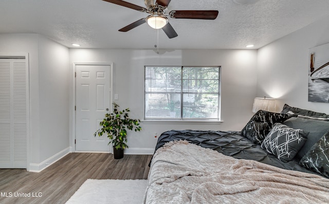 bedroom with hardwood / wood-style floors, ceiling fan, and a textured ceiling