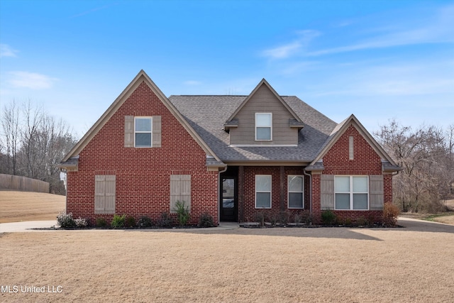 view of front of home with brick siding, a front lawn, and a shingled roof