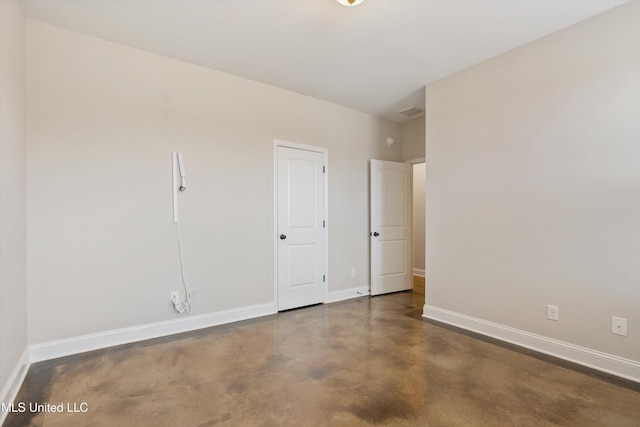 spare room featuring baseboards and concrete flooring