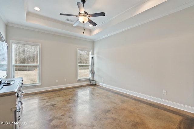 spare room featuring crown molding, ceiling fan, concrete flooring, and a raised ceiling