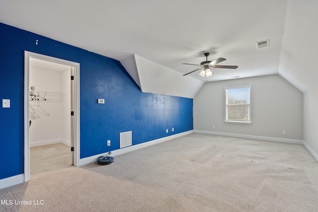 additional living space with ceiling fan, lofted ceiling, light colored carpet, visible vents, and baseboards