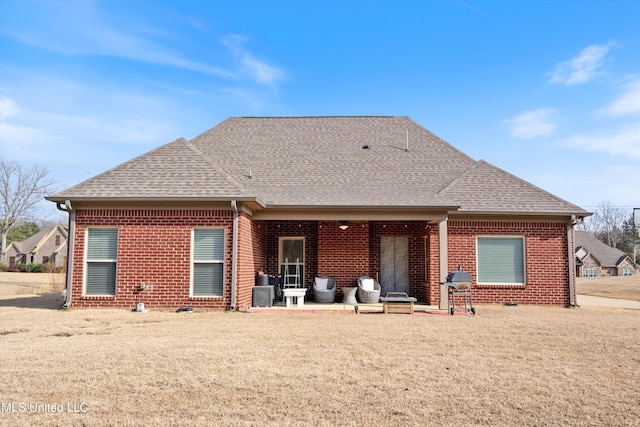 back of property featuring a shingled roof, a patio area, and brick siding