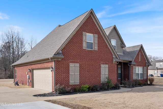 traditional home with driveway, an attached garage, roof with shingles, and brick siding