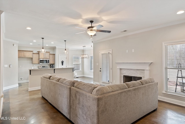 living room with crown molding, a stone fireplace, a wealth of natural light, and ceiling fan