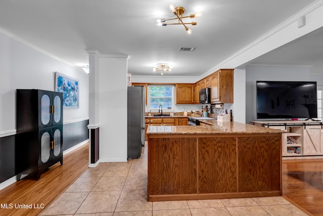 9618 Paige Bayou Rd, Vancleave, MS 39565 - kitchen featuring a peninsula, freestanding refrigerator, ornamental molding, brown cabinetry, and black microwave