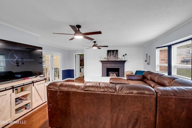 9618 Paige Bayou Rd, Vancleave, MS 39565 - living room with wood finished floors, a ceiling fan, crown molding, a textured ceiling, and a brick fireplace