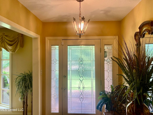 foyer with a textured ceiling, a chandelier, and a wealth of natural light