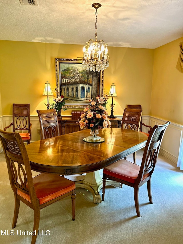 carpeted dining area featuring a textured ceiling and an inviting chandelier