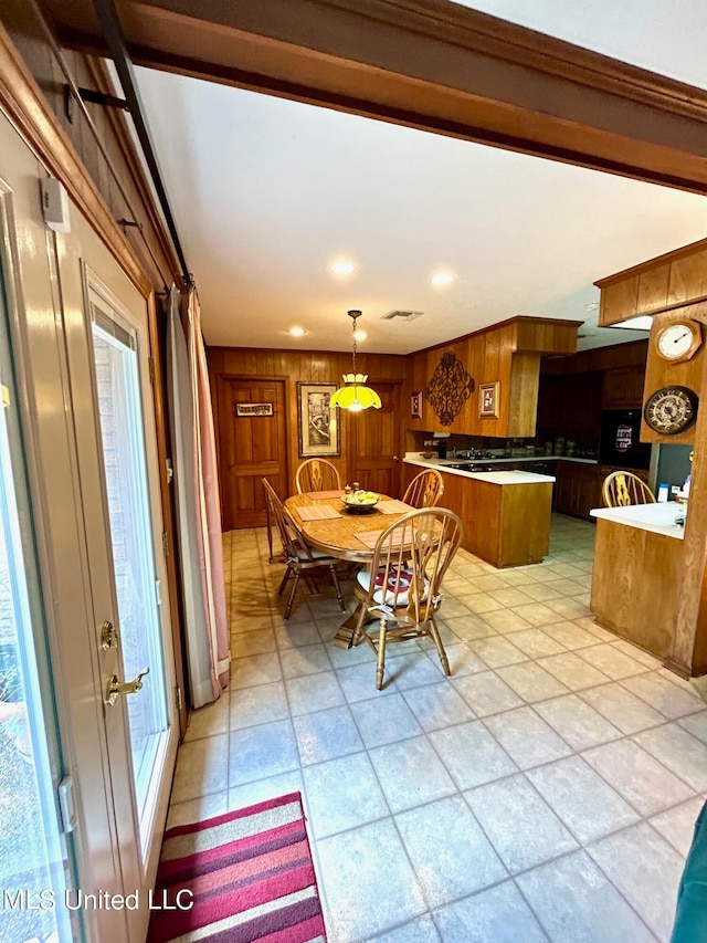 dining area featuring light tile patterned floors and wood walls