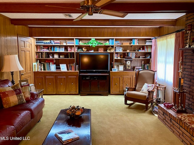 carpeted living room featuring beam ceiling, wood walls, and ceiling fan