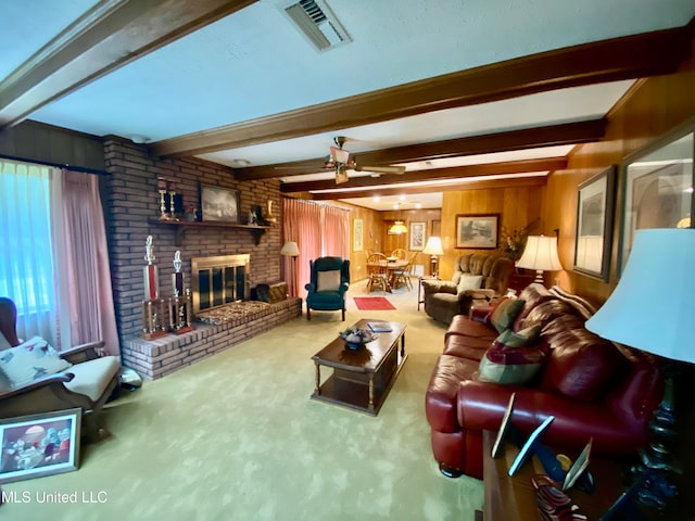 carpeted living room with beam ceiling, wooden walls, a fireplace, and ceiling fan