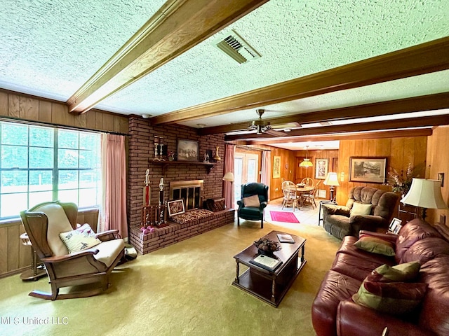 living room with a textured ceiling, wood walls, beamed ceiling, and a brick fireplace