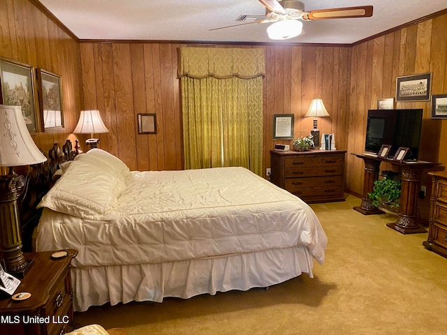 carpeted bedroom with ceiling fan, ornamental molding, and wooden walls