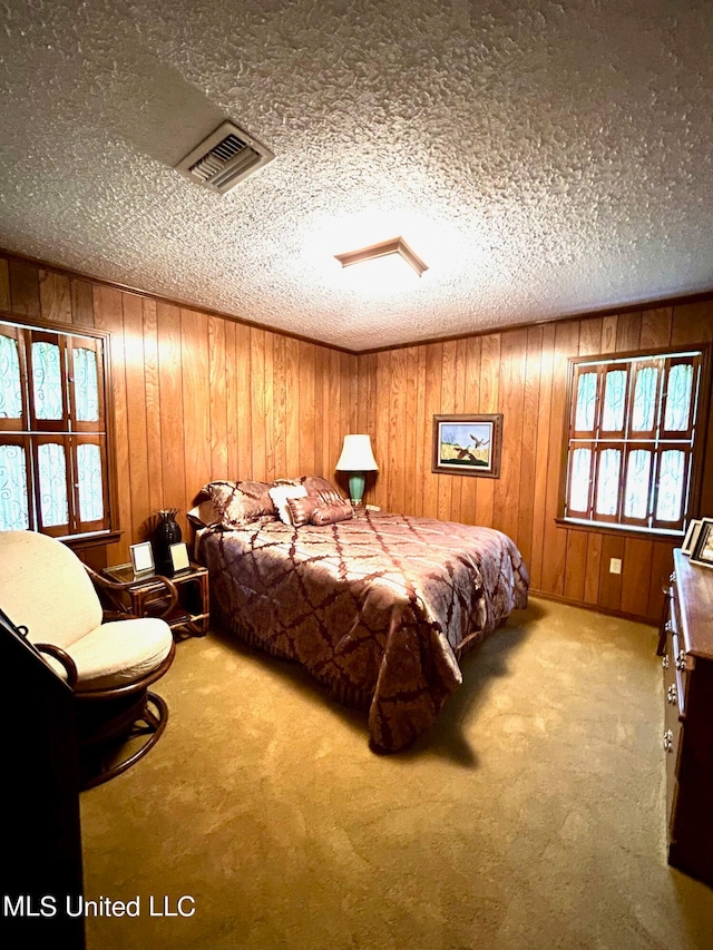 bedroom featuring a textured ceiling, wooden walls, and carpet