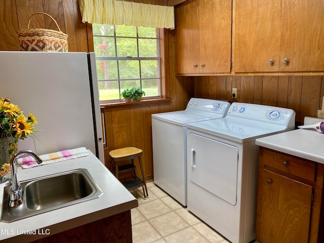 washroom with sink, washer and dryer, wood walls, and cabinets