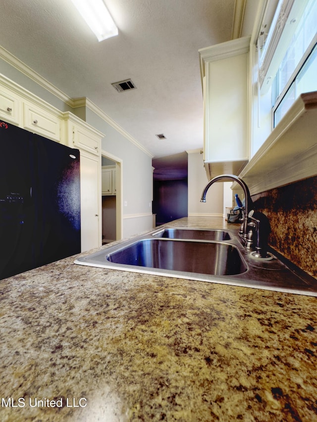 kitchen featuring black refrigerator, crown molding, sink, and a textured ceiling