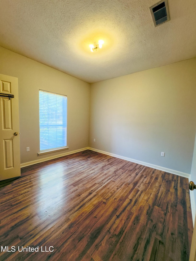 unfurnished room featuring a textured ceiling and dark wood-type flooring