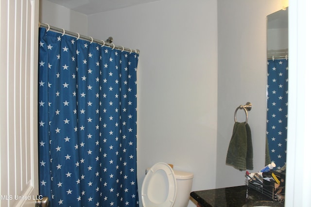 bathroom with toilet, vanity, and walk in shower