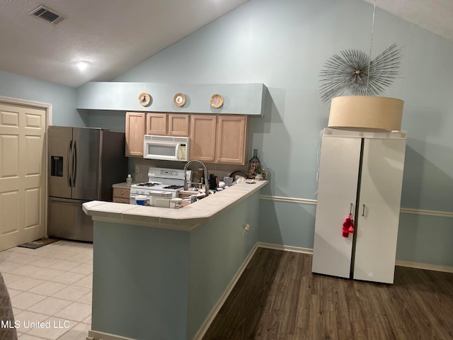 kitchen featuring white appliances, hardwood / wood-style floors, tile countertops, kitchen peninsula, and light brown cabinets